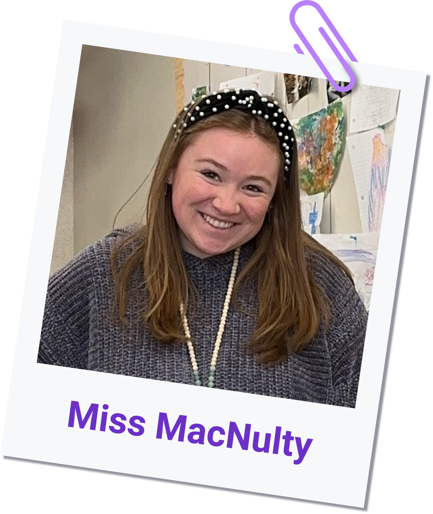 Miss Jenna MacNulty smiles at the camera, wearing a dark knit sweater and a beaded headband. She stands in front of a wall adorned with childrens drawings. Miss MacNulty is written below the photo in purple text. Miss Jenna MacNulty smiles at the camera, wearing a dark knit sweater and a beaded headband. She stands in front of a wall adorned with childrens drawings. Miss MacNulty is written below the photo in purple text.